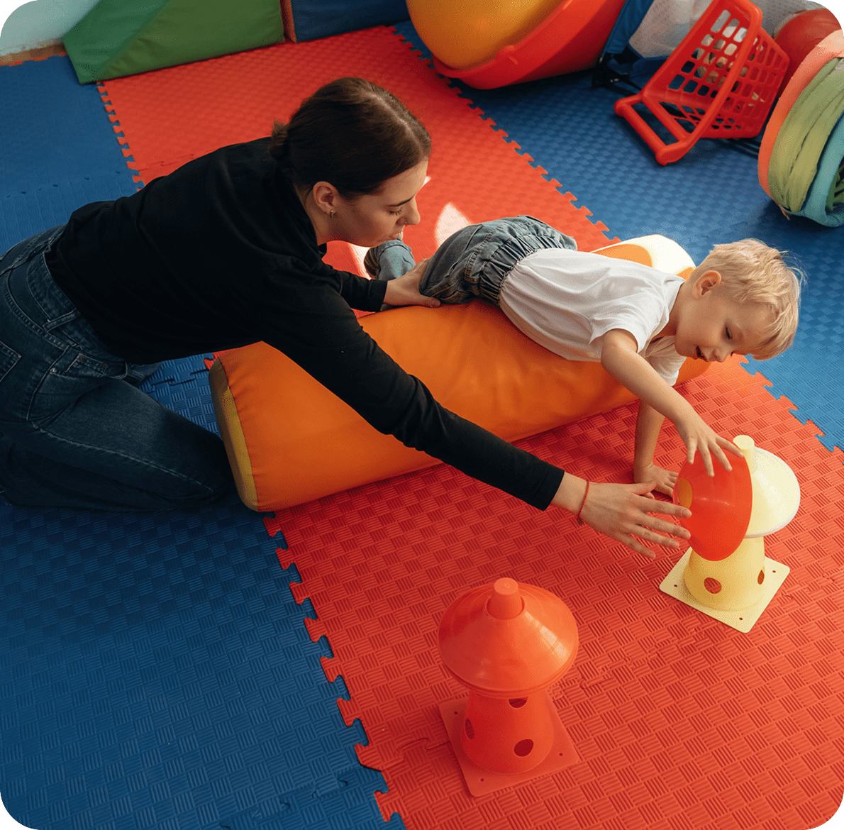 Child playing on mats with supervisor