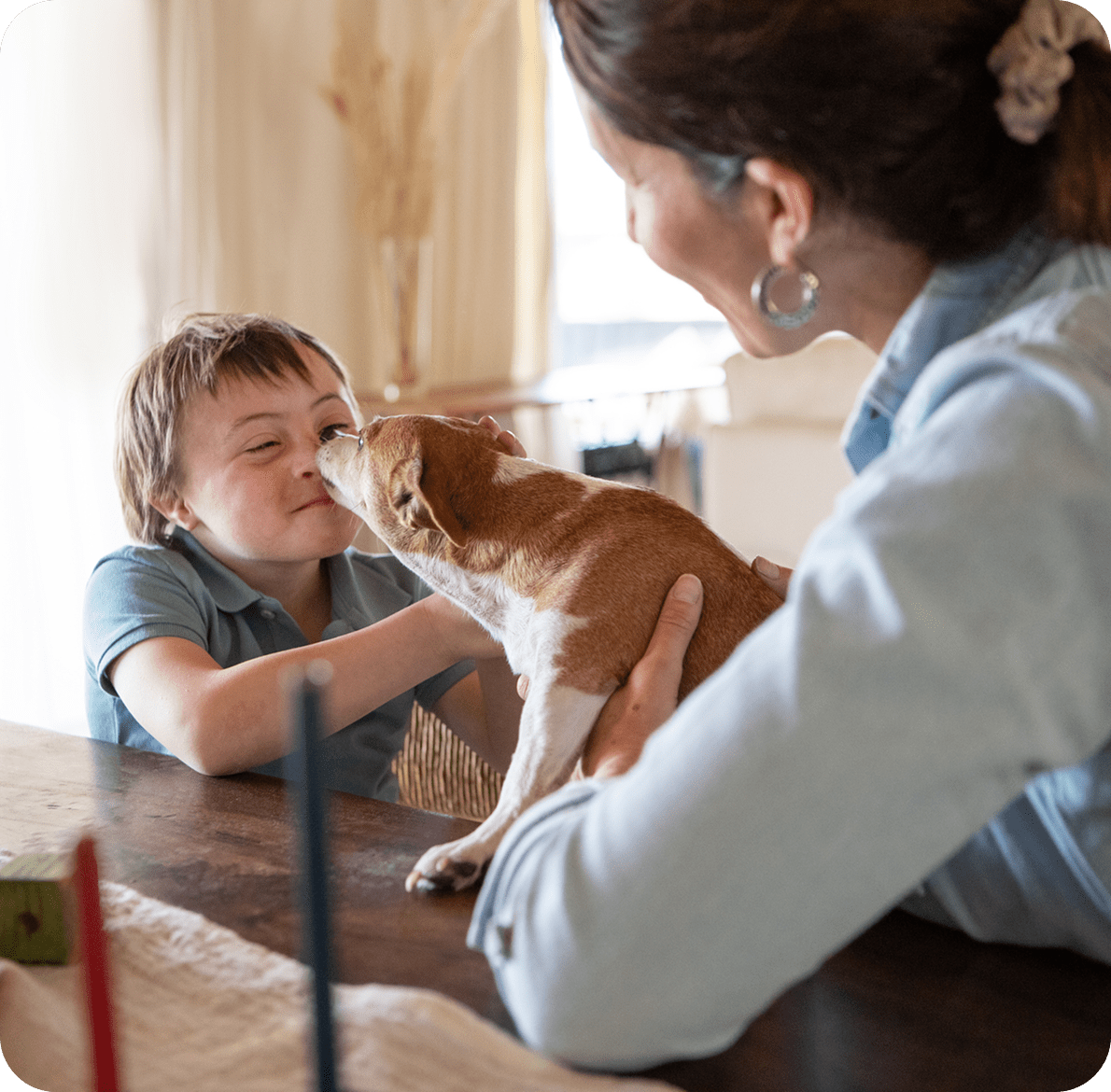Child smiling at dog on table.